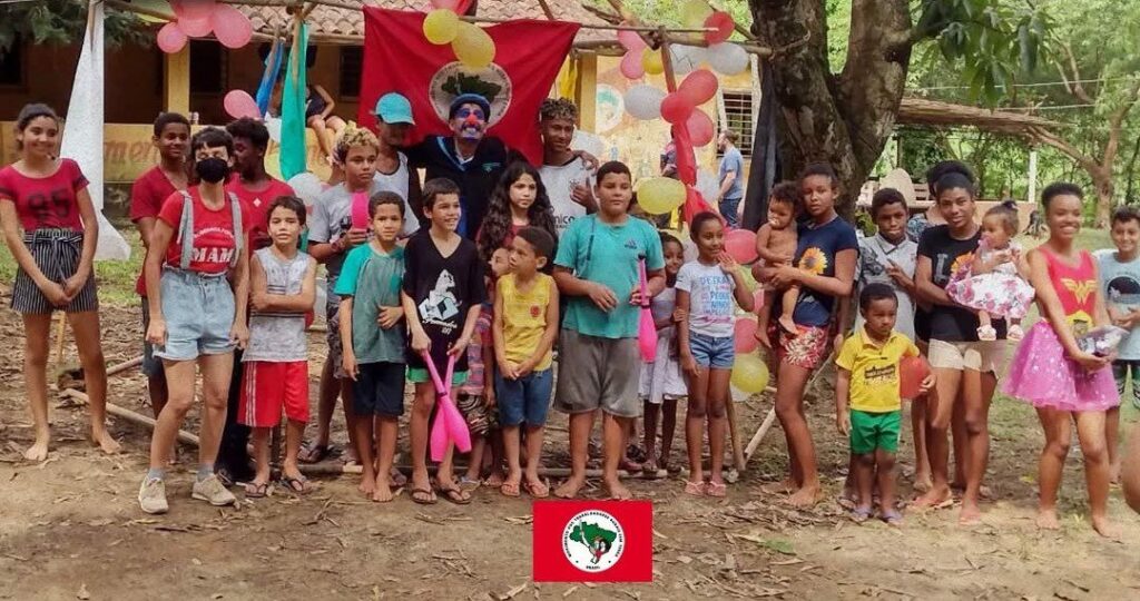 Pessoas em comemoração dos 17 anos do assentamento Olga Benário do MST-MG, em 2022. Na foto, há diversas crianças, com brinquedos e balões pelo quintal.